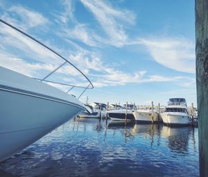 Boats moored at harbor against blue sky