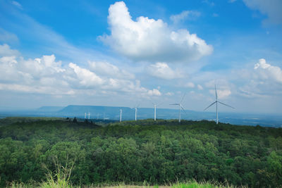 Wind turbines on field against sky