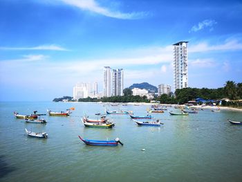 Boats moored on sea by buildings in city against sky