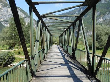 Footbridge amidst trees against sky