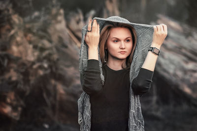 Portrait of young woman standing against trees