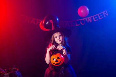 Full length of woman with arms outstretched standing against illuminated red background