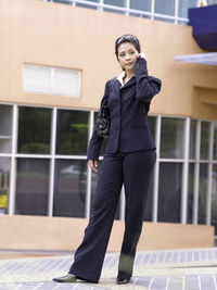 Businesswoman talking on phone while standing against building