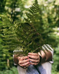 Midsection of woman holding leaves over face