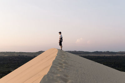 Woman walking on road against sky during sunset