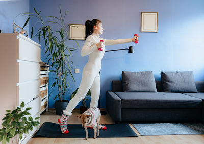 Full length of young woman sitting on sofa at home