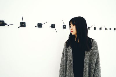 Mid adult woman looking away while standing against wall