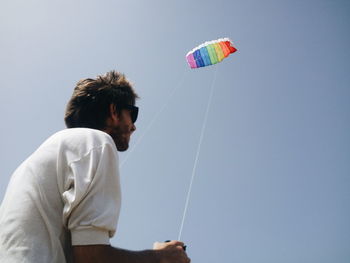 Low angle view of man flying kite against clear sky