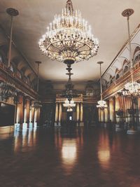 Illuminated chandelier hanging on ceiling of building