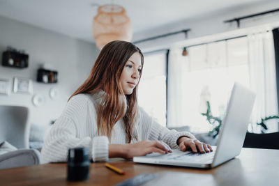 Girl using laptop on table at home