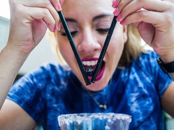 Close-up of woman having blueberry with straws