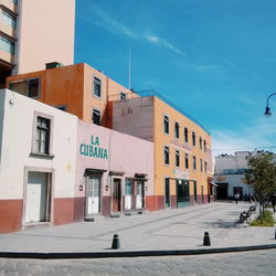 Street by buildings in city against sky