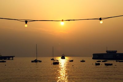 Silhouette boats in sea against sky during sunset