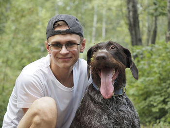 Portrait, a young man of european appearance with a dog in the forest. high quality photo