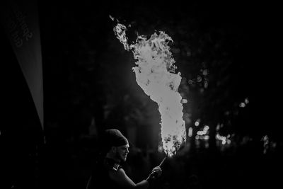 Side view of boy holding bubbles in water at night