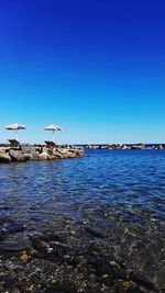 Calm sea against clear blue sky