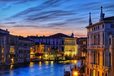 Illuminated buildings in city against sky at sunset