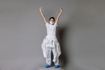 Portrait of woman with arms raised standing against gray background