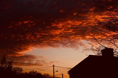 Low angle view of silhouette trees and buildings against sky during sunset