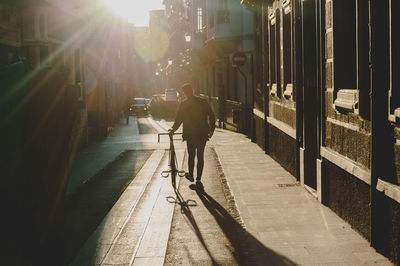 Rear view of man walking on sidewalk in city