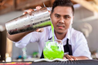 Male bartender preparing cocktail in bar