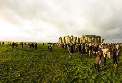 Crowd at stonehenge against cloudy sky