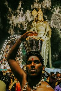 Man standing against statue during traditional ceremony