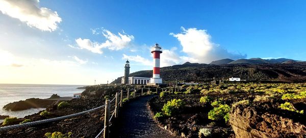 Lighthouse by sea against sky