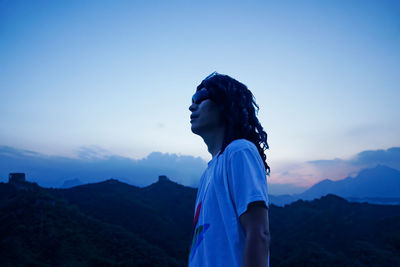 Side view of man looking away against sky during sunset