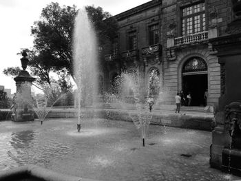 Fountain in park against buildings in city