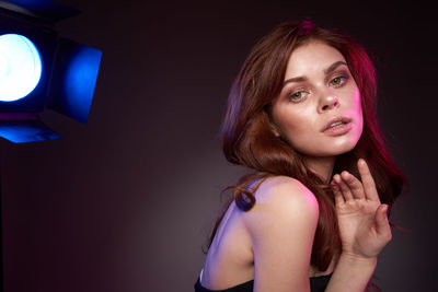 Portrait of beautiful young woman against black background