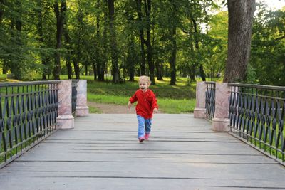 Rear view of boy running on footbridge