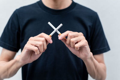 Midsection of man holding cigarette against gray background