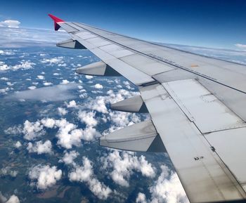 Airplane flying over clouds against blue sky