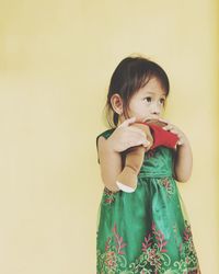 Cute girl with toy standing against wall