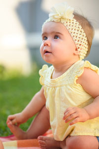 Cute girl in yellow baby clothing at back yard