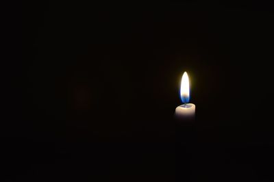 Close-up of lit candle against black background