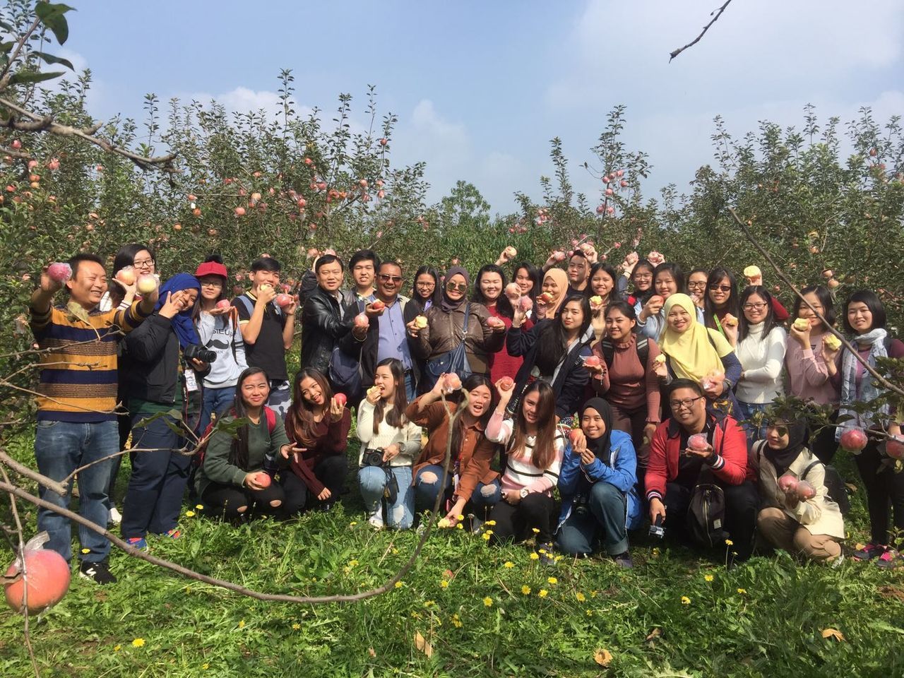 large group of people, real people, leisure activity, day, togetherness, men, grass, casual clothing, tree, outdoors, lifestyles, celebration, field, women, sitting, young women, nature, standing, young adult, crowd, portrait, sky, people