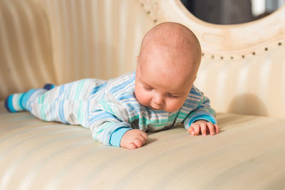 Portrait of cute baby boy lying on bed at home