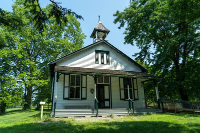 An old one room school under the spreadin oak and maple trees.