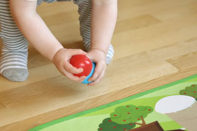 Low section of child playing with tomato at home