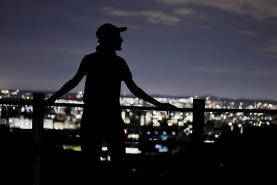Silhouette man standing by railing against sky at night