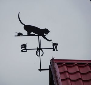Low angle view of weather vane against sky