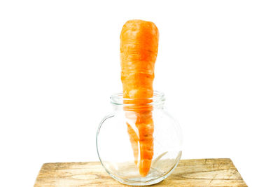 Close-up of orange glass on table against white background