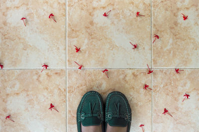 Low section of woman with red flowers standing on tiled floor