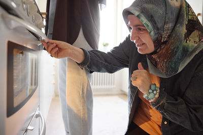 Woman checking food for eid al-fitr in oven