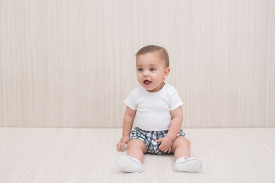 Portrait of cute girl sitting against wall