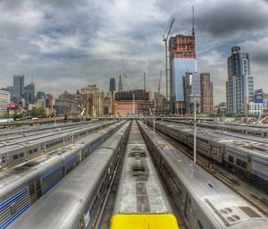 Railroad tracks in city against cloudy sky