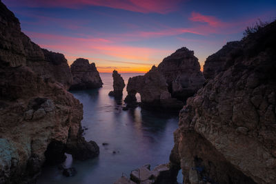 Rocks on sea against sky during sunset