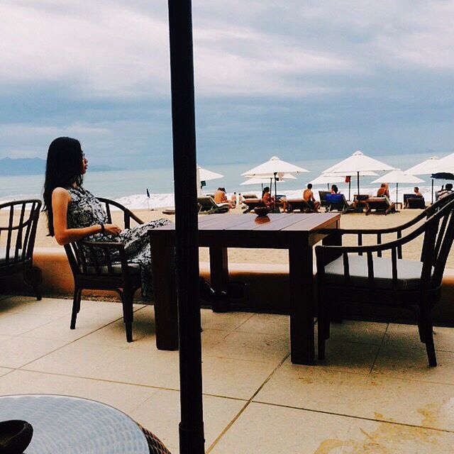 PEOPLE SITTING ON CHAIR AT SEASIDE